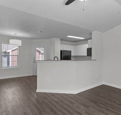 an empty living room and kitchen with a counter top and a refrigerator