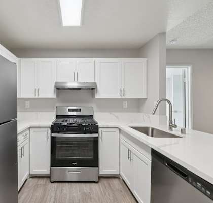 A modern kitchen with a stainless steel refrigerator and white cabinets.