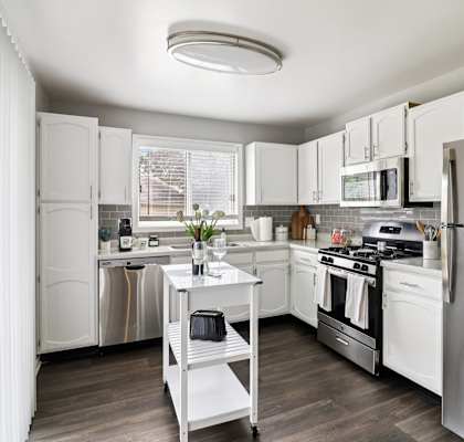 Open-concept kitchen with white cabinets and stainless steel fridge at Ashford at Geneva – pet-friendly apartments in Geneva, IL