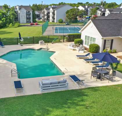 A large outdoor swimming pool surrounded by lounge chairs and umbrellas.