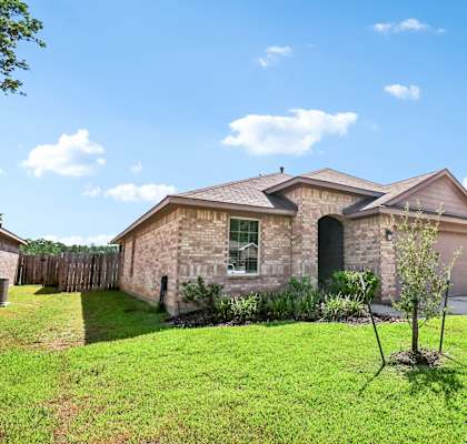 A house with a brown roof and a green lawn in front.