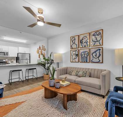 A living room with a couch, a coffee table, and a fan.
