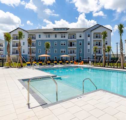 A swimming pool in front of a multi-story apartment building.