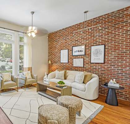 A living room with a white couch, a chair, a table, and a plant.