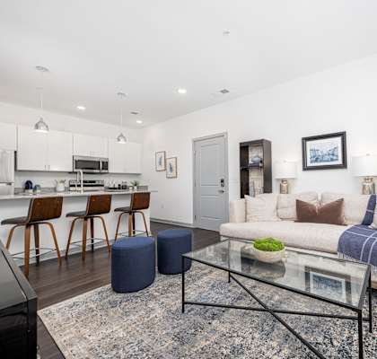 A modern living room with a glass coffee table and a grey sofa.