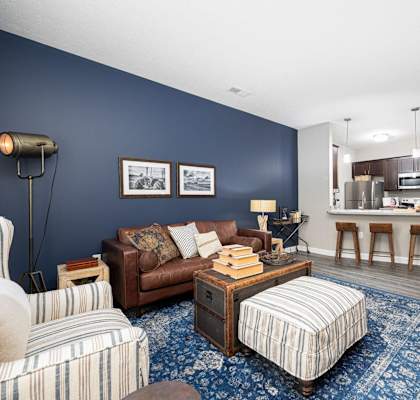 a living room with a couch and a chair in front of a kitchen