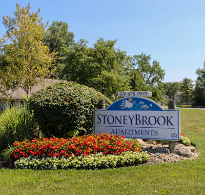 the sign for stone brook addtions in front of a garden with colorful flowers