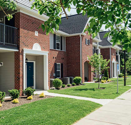 a brick building with a porch and a sidewalk