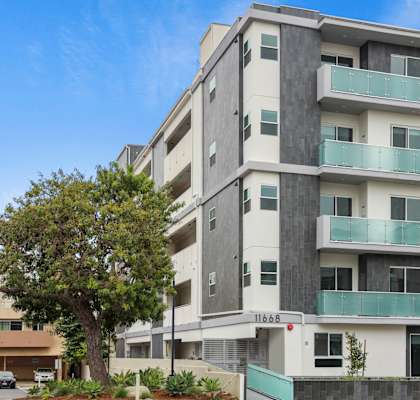 an image of an apartment building with balconies and a tree