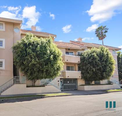 an apartment building with a driveway and trees in front of it