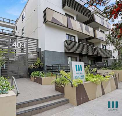 an apartment building with stairs and plants in front of it