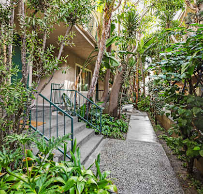 A pathway with a metal railing on the left side and a building in the background.