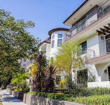 a large white house with a balcony and a sidewalk