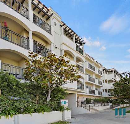 a large white apartment building with trees and plants in front of it