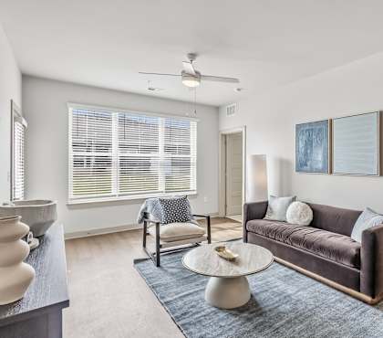 A living room with a brown couch and a ceiling fan.