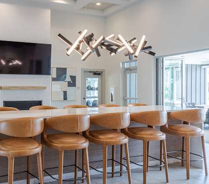 A modern bar area with a fireplace and leather stools. at Viridian Apartments LLC Apartments, Kentucky