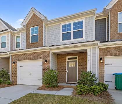 A row of townhomes with garages and front yards.
