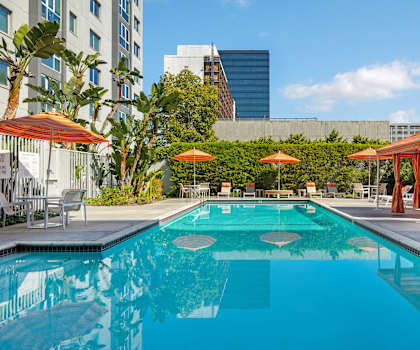 A swimming pool surrounded by orange umbrellas and lounge chairs.