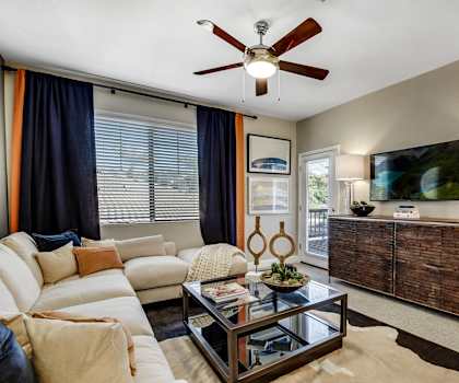 The living room with a couch, coffee table, decorations, a TV, and balcony at Desert Club.