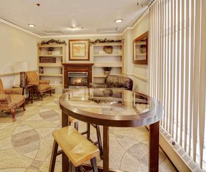 The resident lounge with a fireplace, couches, decorations, plush chairs, and coffee tables at Mendenhall Tower Apartments. 