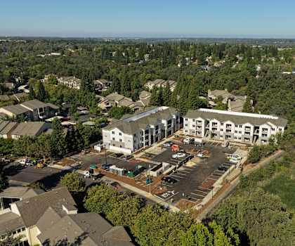 A large white building surrounded by trees and a parking lot.