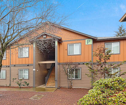 A building with a brown and orange exterior and a large tree in front.