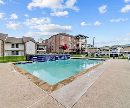 A swimming pool surrounded by a concrete floor and a fence.
