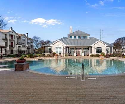 A large swimming pool in front of a building with a fountain in the middle.
