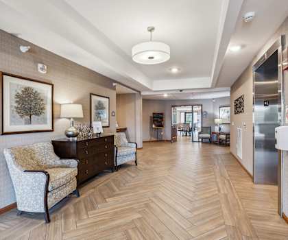 a hallway with chairs and paintings on the walls and a wood floor