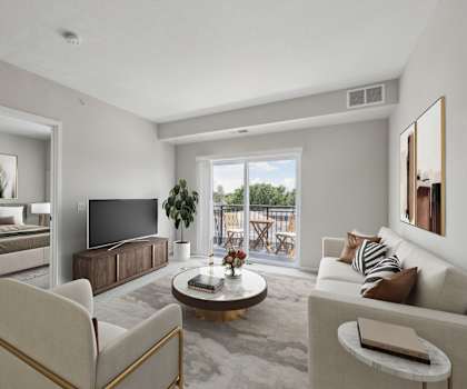 A living room with a television, a chair, a table, and a plant.