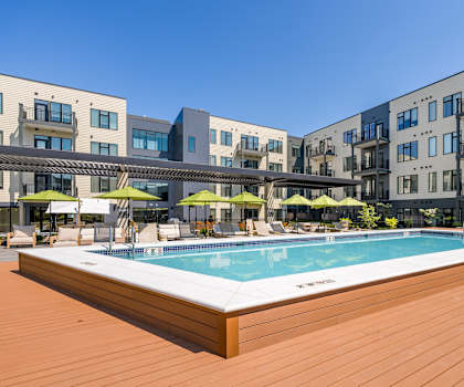 A pool surrounded by wooden deck and buildings.