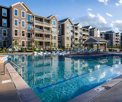 a large swimming pool with an apartment building in the background at The Clearing at ONE28, Olathe, 66062