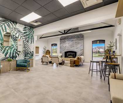 the lobby of a building with tables and chairs and a fireplace