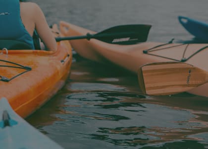 A person is kayaking on a calm body of water.