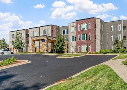 A multi-story apartment building with a parking lot in front.