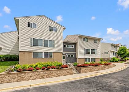 an apartment building with a stone retaining wall and flower beds