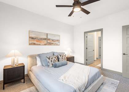 A bedroom with a bed, nightstand, and a painting on the wall.