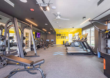 A gym with a variety of equipment including treadmills, weights, and exercise machines.