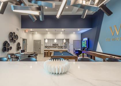 A pool table is in the middle of a room with a white marble table.