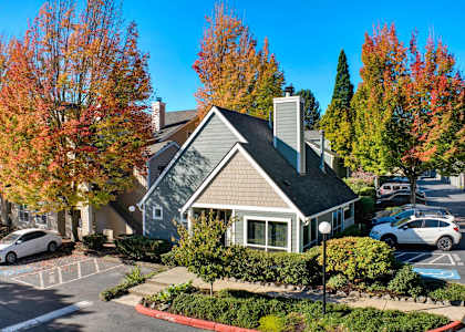 a small house in a parking lot with cars in front of it