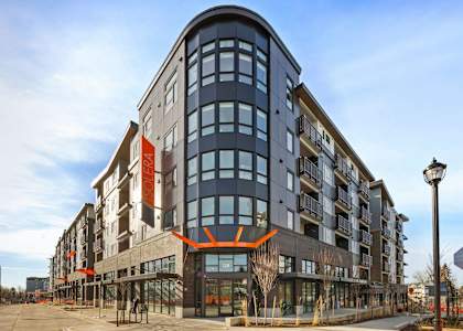 A modern building with a curved facade and a large orange logo on the front.