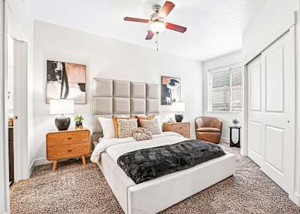 A bedroom with a large bed and a ceiling fan.