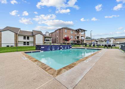 A swimming pool surrounded by a concrete floor and a fence.
