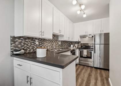 A kitchen with white cabinets and a black countertop.