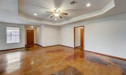 an empty living room with a ceiling fan and a window