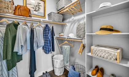 A closet with clothes and shoes on shelves and hangers.