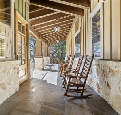 a porch with wooden rocking chairs and marble walls