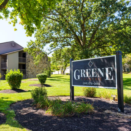 a sign that says greene apartments with a building in the background