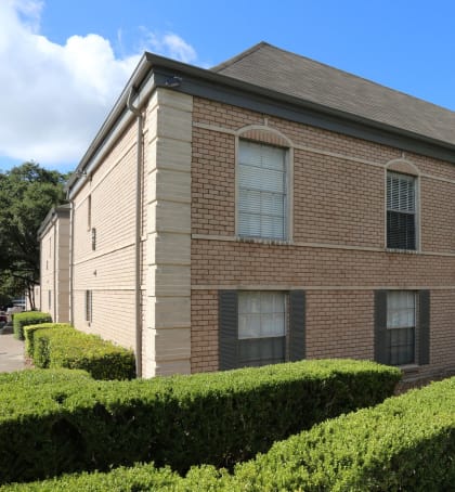 a brick building with hedges in front of it