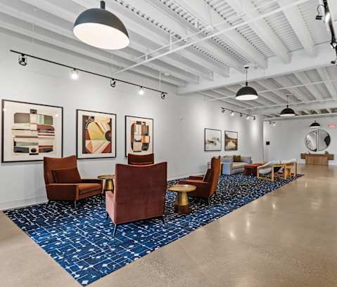 A spacious room with a blue carpet and brown chairs.